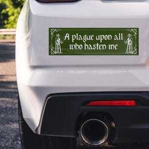 May include: A rectangular dark green bumper sticker featuring white decorative filigree borders and two white plague doctor illustrations. The text in the center reads, A plague upon all who hasten me, written in a stylized, gothic-inspired font.