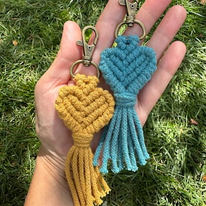 May include: Two handmade macrame keychains with tassels. One keychain is teal blue and the other is mustard yellow.