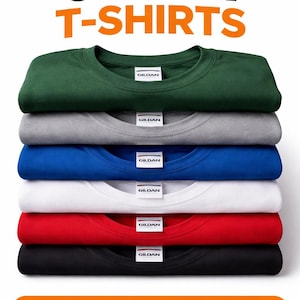 Op de afbeelding: Een stapel van zes opgevouwen t-shirts in verschillende kleuren: groen, grijs, blauw, wit, rood en zwart. De tekst "6 PACK T-SHIRTS" staat bovenaan en "PICK YOUR COLORS!" onderaan. Elk shirt heeft een Gildan-label.