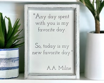 May include: White wooden sign with a black painted quote by A.A. Milne: "Any day spent with you is my favorite day. So, today is my new favorite day."