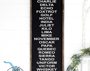 May include: Black chalkboard sign with white text listing the NATO phonetic alphabet. The sign is framed in wood and has a rustic look. The text on the sign reads: Alpha, Bravo, Charlie, Delta, Echo, Foxtrot, Golf, Hotel, India, Juliet, Kilo, Lima, Mike, November, Oscar, Papa, Quebec, Romeo, Sierra, Tango, Uniform, Victor, Whiskey, X-Ray, Yankee, Zulu.