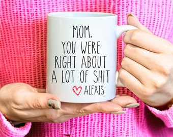 May include: White ceramic coffee mug with black text that reads "Mom, you were right about a lot of shit" with a red heart and the name "Alexis" below the text.