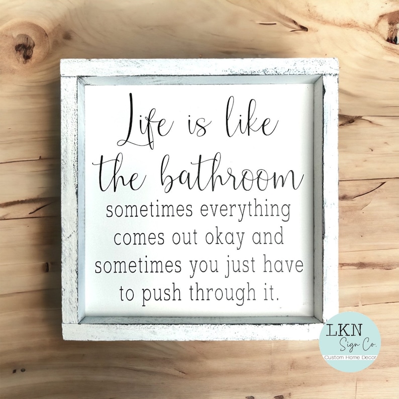 May include: White framed sign with the text "Life is like the bathroom, sometimes everything comes out okay and sometimes you just have to push through it." The sign is a custom home decor item.