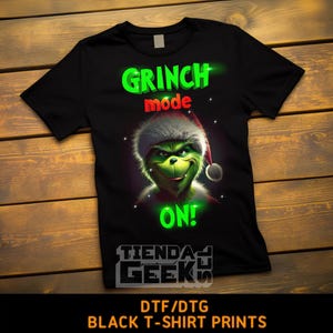 Puede incluir: Camiseta negra con un personaje verde del Grinch que lleva un gorro de Papá Noel. El texto "Grinch mode on!" está escrito en verde en la camiseta. El texto "TIENDA GEEKS" está escrito en blanco en la parte inferior de la camiseta.