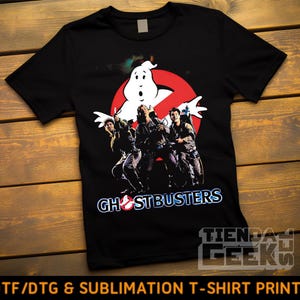 Puede incluir: Camiseta negra con el logo de los Cazafantasmas, con el fantasma icónico y el equipo de los Cazafantasmas. El texto "GHOSTBUSTERS" está en azul y blanco. La parte inferior de la camiseta tiene el texto "DTF/DTG & SUBLIMATION T-SHIRT PRINTS".