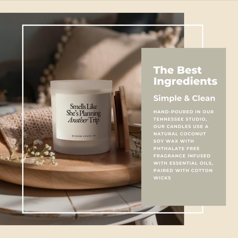 May include: A frosted glass candle with the text "Smells Like She's Planning Another Trip" on a white label. The candle sits on a wooden tray with a wooden lid and sprigs of white flowers. The background is blurred.