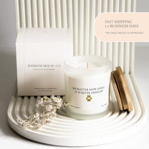 May include: A white candle in a frosted glass jar with a wooden lid, and a white box. The candle has the text "NO MATTER HOW LONG, IT IS NEVER ENOUGH" and a paw print. The box says "WISDOM HOUSE CO".