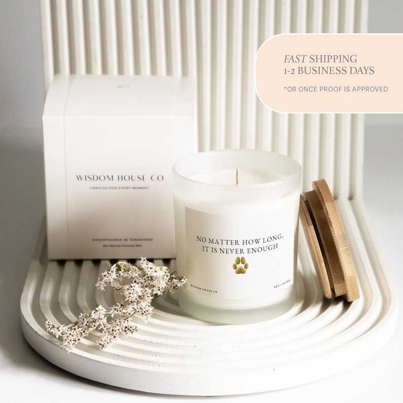 May include: A white candle in a frosted glass jar with a wooden lid, and a white box. The candle has the text "NO MATTER HOW LONG, IT IS NEVER ENOUGH" and a paw print. The box says "WISDOM HOUSE CO".
