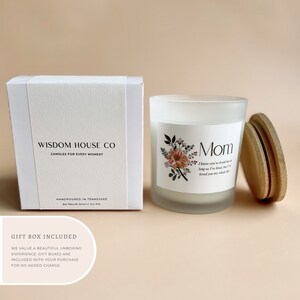 May include: White candle with a frosted glass jar and a wooden lid. The candle has a floral design and the text "Mom" with a quote about love. The candle is packaged in a white box with the text "Wisdom House Co. Candles for Every Moment" and "Handpoured in Tennessee".