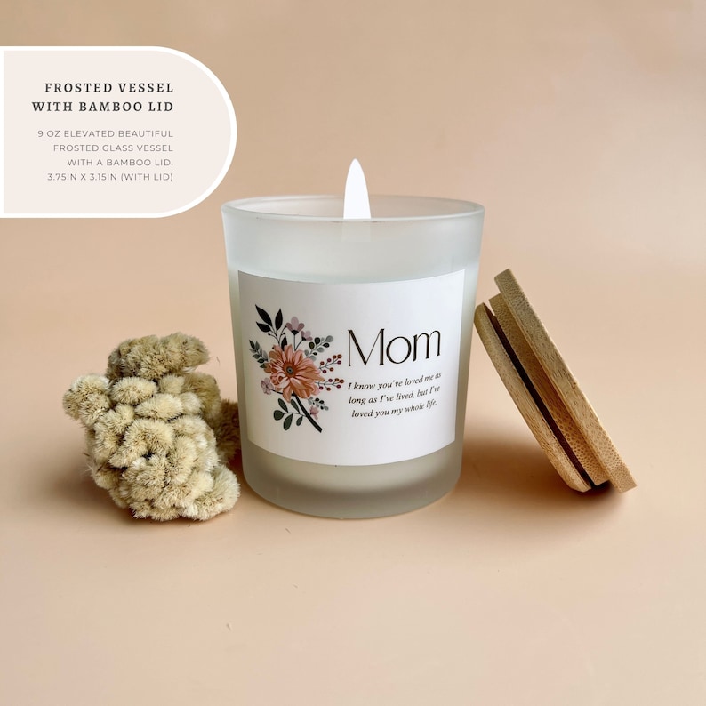 May include: A frosted glass candle with a bamboo lid. The candle is 9 ounces and measures 3.75 inches by 3.15 inches. The candle has a floral design and the text "Mom" and "I know you've loved me as long as I've lived, but I've loved you my whole life".