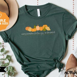 May include: Forest green t-shirt featuring a line of illustrated pumpkins in various shapes and colors. The text "every pumpkin belongs in the patch" is printed below the pumpkins. The shirt is displayed with a hat and other accessories.