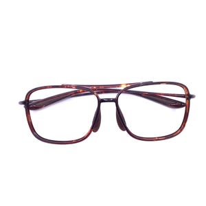 May include: Aviator-style eyeglasses featuring a brown tortoiseshell pattern frame. The glasses have a double bridge design, rectangular lenses with rounded corners, and dark brown nose pads. The temples are thin and match the frame pattern.