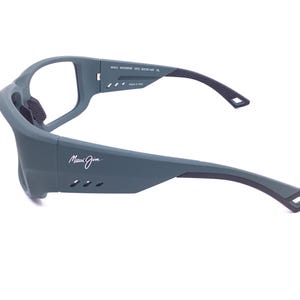 May include: Matte gray sunglasses with a wrap-around frame design. The side arms feature the Maui Jim logo in white, three small ventilation slits, and black rubberized grip inserts. The interior temple text reads Maui MJ-800538 003 62-15-125 XL.