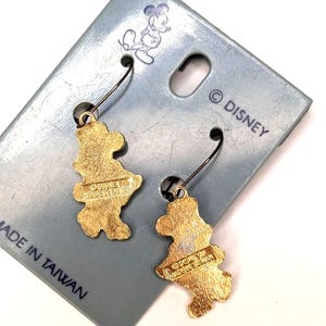 May include: A pair of gold-colored Mickey Mouse earrings on a light blue card. The earrings are shaped like Mickey Mouse and have black ear wires. The card has a Mickey Mouse illustration and the text "&copy; DISNEY MADE IN TAIWAN."