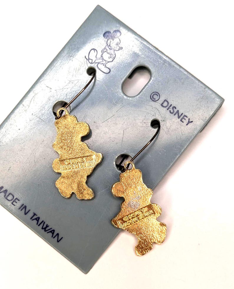 May include: A pair of gold-colored Mickey Mouse earrings on a light blue card. The earrings are shaped like Mickey Mouse and have black ear wires. The card has a Mickey Mouse illustration and the text "&copy; DISNEY MADE IN TAIWAN."