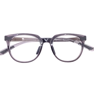 May include: Gray eyeglasses with a rounded frame and clear lenses. The temples are a lighter gray color. The glasses are set against a white background.
