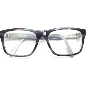 May include: Black and gray rectangular eyeglasses with clear lenses. The frames have a subtle gradient effect, transitioning from black to gray. The temples are a light gray color. The glasses are set against a white background.