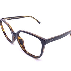 May include: A pair of eyeglasses with a tortoiseshell pattern on the frames and temples. The frames have a square shape with a black accent on the front. The temples are dark brown with a logo near the hinges. The glasses are set against a white background.