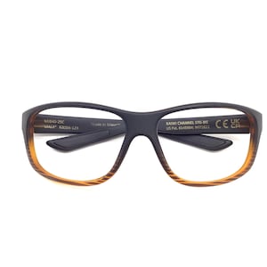 May include: Black and brown eyeglasses with a gradient amber-colored frame. The glasses have a rectangular shape and feature the text "MAUI" and "KAWI CHANNEL STG-60" on the arms. The frame is made of a durable material.