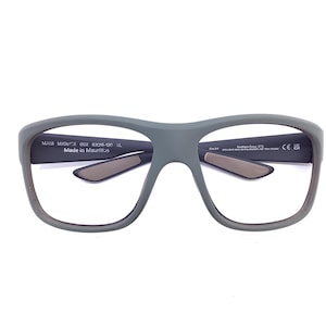 May include: Grey eyeglasses with a thick frame. The glasses have a rectangular shape and a dark grey interior. The text "MAUI MJ01" is printed on the left arm, and "Southern Cross" is printed on the right arm. Made in Mauritius.