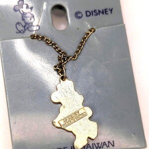 May include: Vintage Mickey Mouse pendant on a chain, attached to a blue card. The pendant is gold-colored and shaped like Mickey Mouse. The card has the Disney logo and the text "MADE IN TAIWAN".