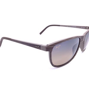 May include: Maui Jim sunglasses featuring a brown and grey wood-grain patterned frame with thin temples. The lenses have a gradient tint, and the Maui Jim logo is printed in gold on the upper right lens and the outer side of the left temple.