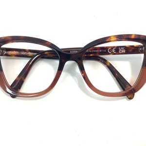May include: Tortoise shell cat eye glasses with brown tinted lenses. The glasses have the text "BLOSSOM" and "CE UK CR" on the side.