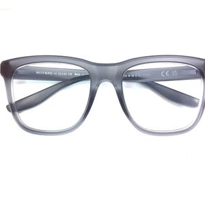 May include: Gray rectangular eyeglasses with clear lenses. The frame has the text "MAUI JIM ML3023-14 55□20-138 Made in China" printed on the right arm and "CE UK 2B" printed on the left arm.