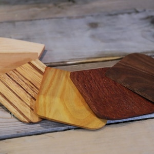 May include: Six different wooden coasters in various shades of brown, yellow, and light brown. The coasters are made from different types of wood, including walnut, maple, and cherry.