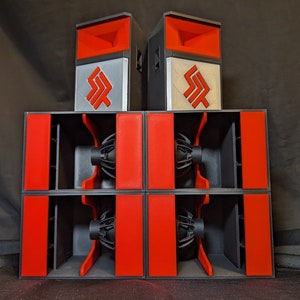 May include: A set of four black and red speaker cabinets with two black and silver speakers on top. The speakers have a logo with the letters "SF" in a stylized font.