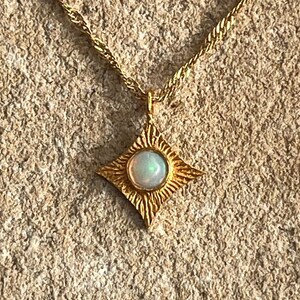 May include: A gold necklace with a star-shaped pendant featuring a white opal gemstone.