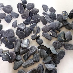 May include: A collection of smooth, gray river rocks with natural patterns of light and dark gray stripes. The stones vary in size and shape, ideal for decorative landscaping or craft projects.