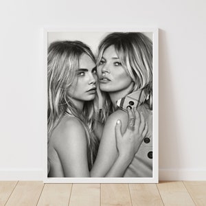 Può includere: Fotografia in bianco e nero di due donne, una con un braccio intorno all'altra. La donna in primo piano indossa un trench con una fodera a motivi. La donna sullo sfondo è a torso nudo.