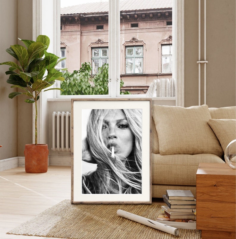 May include: Black and white photograph of a woman with long hair, looking directly at the camera. She is holding a cigarette in her mouth and has a serious expression on her face.
