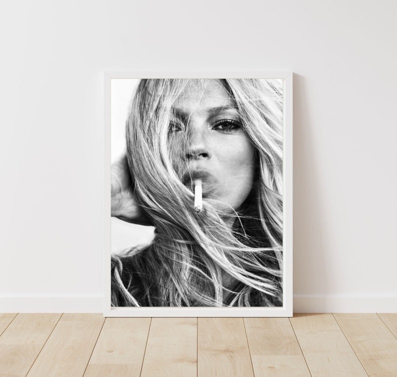 May include: Black and white portrait photograph of a woman with long, flowing hair. She is looking directly at the camera and has a cigarette in her mouth.