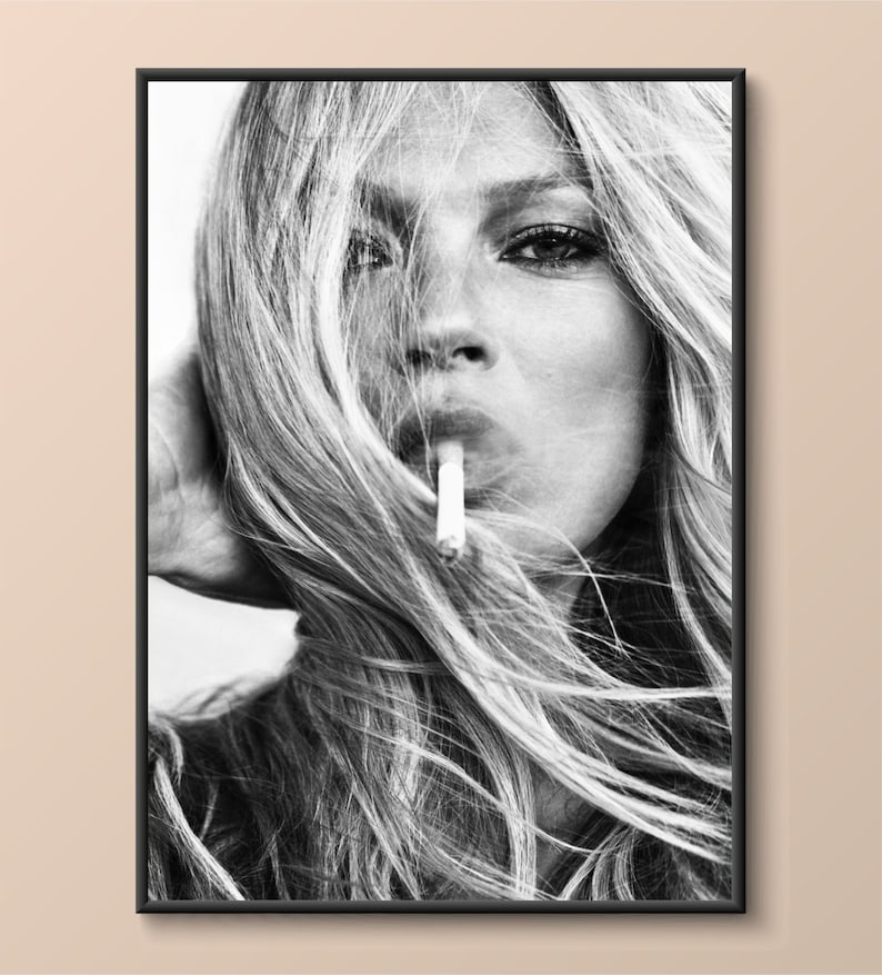 May include: Black and white photograph of a woman with long, flowing hair. She is looking directly at the camera and has a cigarette in her mouth.