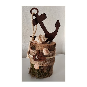 Könnte beinhalten: Ein rustikaler Holzstamm mit einer Jute-Ummantelung und einem Metallanker oben. Der Stamm ist mit Muscheln und Moos verziert.