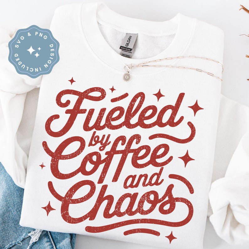 May include: White sweatshirt with the phrase "Fueled by Coffee and Chaos" in red, distressed lettering. The design includes star accents. A silver necklace with a small pendant is draped across the sweatshirt. The image also includes a blue and white SVG and PNG design.