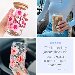 May include: Clear glass can-shaped drinking glasses with decorative designs. One glass features pink smiling flower and star stickers, another has white flower stickers, and a third has "GIRL POWER" heart stickers.