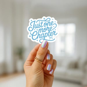 K&ouml;nnte beinhalten: Ein hellblauer Aufkleber mit dem Text "Just one more Chapter" in einer verspielten Schriftart. Der Aufkleber hat eine wolkenartige Form mit kleinen Sternen und einer Schleife. Der Aufkleber wird von einer Hand mit schillernden N&auml;geln und goldenen Ringen gehalten.