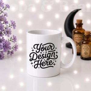 May include: A white ceramic mug featuring the black text Your Design Here in a stylized script font, accented by small four-pointed stars. The mug has a smooth finish, a curved handle, and a cylindrical body, presented as a blank template for custom graphics.