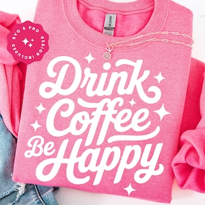 Può includere: Una felpa rosa con le parole "Drink Coffee Be Happy" in corsivo bianco e una collana. La felpa ha girocollo e maniche lunghe. Il design include accenti di stelle. L'immagine include anche un design SVG e PNG rosa.
