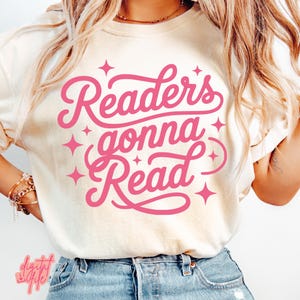 Op de afbeelding: Crèmekleurig T-shirt met de roze tekst "Readers gonna Read" en sterren. Dit casual shirt is geschikt voor dagelijks gebruik. Het ontwerp staat centraal op de voorkant.