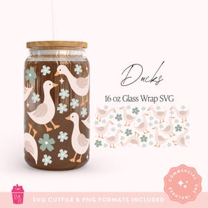 Puede incluir: Un diseño de envoltura de vidrio con un patrón de patos y flores en marrón claro, blanco y verde salvia. También se muestran las palabras "Ducks" y "16 oz Glass Wrap SVG". El vaso tiene una tapa de madera y una pajita. El vaso contiene aproximadamente 473 ml.