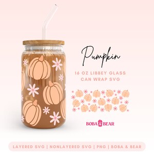 May include: A 16 ounce glass jar with a wooden lid and a straw. The jar is decorated with a pattern of orange pumpkins and pink flowers. The text "Pumpkin 16 oz Libbey Glass Can Wrap SVG" is written in black cursive font. The text "BOBA BEAR" is written in pink and white font. The text "LAYERED SVG | NONLAYERED SVG | PNG | BOBA & BEAR" is written in black font.