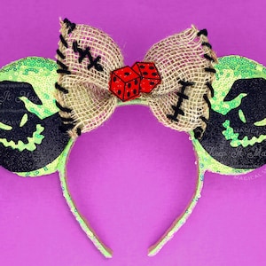 May include: A Halloween-themed headband with mouse ears. The ears are lime green with black glitter silhouettes of a character's face. A burlap bow with red dice and black stitching accents the headband. The headband is covered in green sequins.