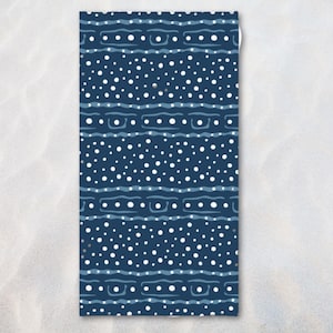 May include: A rectangular beach towel with a navy blue background and a repeating pattern of white polka dots and wavy lines. The towel's design features horizontal bands of dots and lines, creating a visually appealing and modern aesthetic.