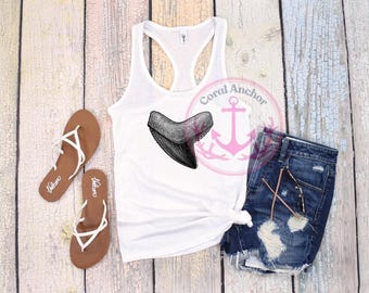 May include: White tank top with a black and gray shark tooth graphic. The image also includes denim shorts, brown sandals, and a pink logo with the words "Coral Anchor".