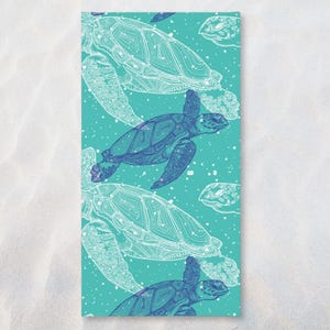 Puede incluir: Una toalla de playa rectangular con un fondo turquesa y un patrón de tortugas marinas. Las tortugas están representadas en tonos azules y blancos, con contornos detallados y patrones internos. Pequeños puntos blancos.
