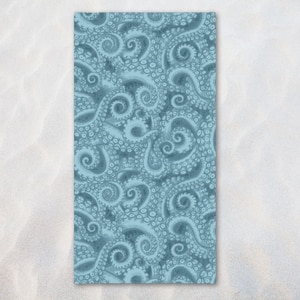 May include: A rectangular beach towel with a repeating pattern of blue octopus tentacles. The tentacles have a detailed, textured appearance with suction cups visible. The background is a light blue colour.